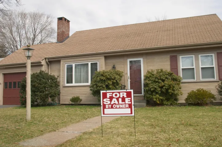 For sale sign in front of a house in Detroit, MI, promoting the option of selling your home for cash
